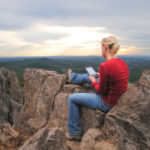My wife reading her Kindle on a mountain by Ryan Smith